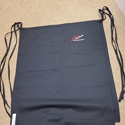 Black server apron with a red and white embroidered restaurant logo on the pocket, custom embroidery by Dad Bod Screen Printing