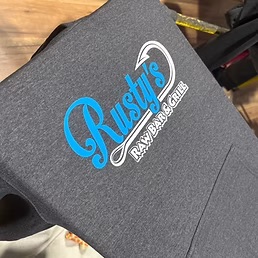 Rusty's Raw Bar & Grill logo screen printed in bright blue and white on a charcoal heather t-shirt by Dad Bod Screen Printing
